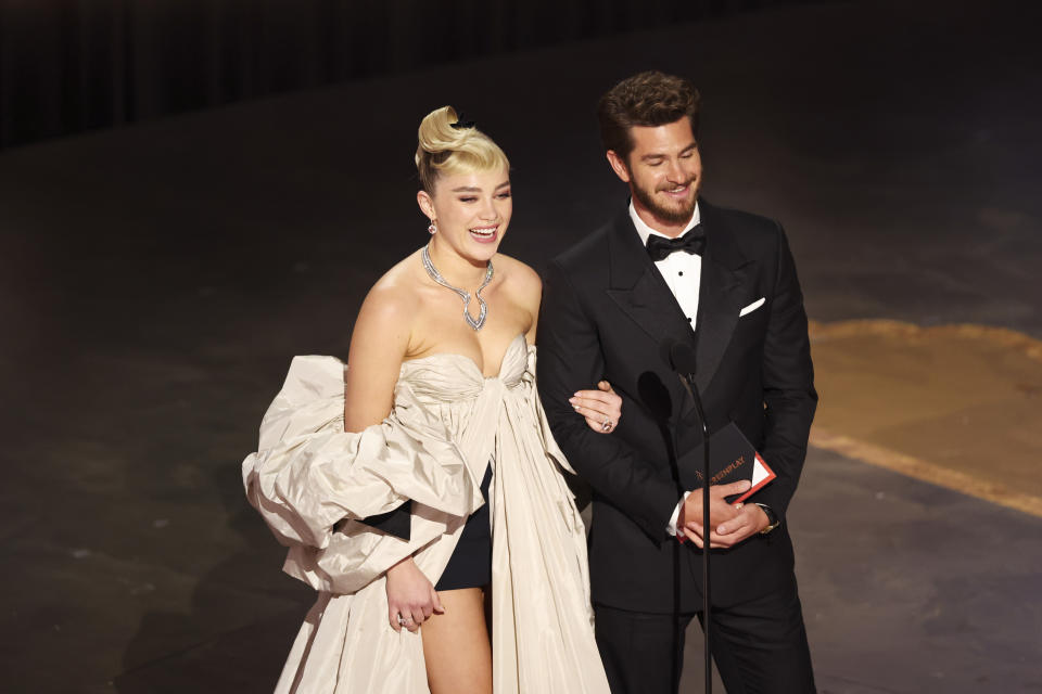 Florence Pugh links arms with Andrew Garfield as they appear onstage together at an awards show