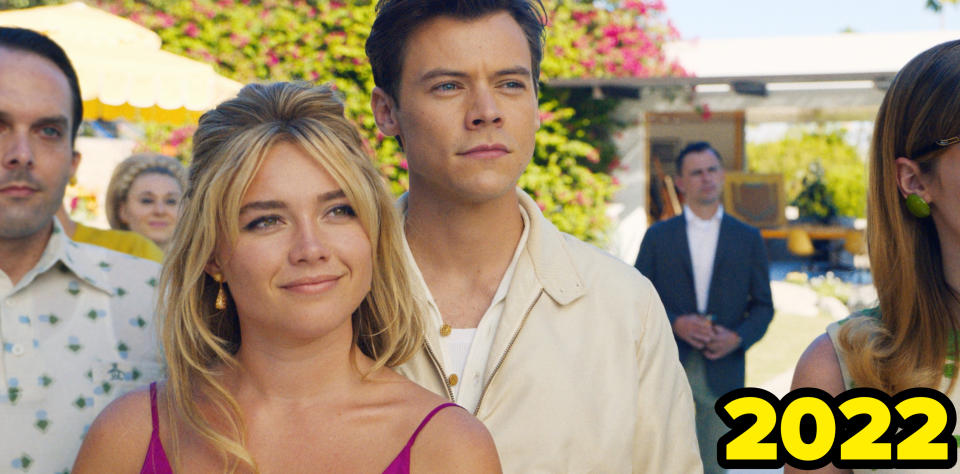 Florence Pugh wears a tank style dress and a small pouf while Harry Styles stands behind her in a jacket in a scene from Don't Worry Darling