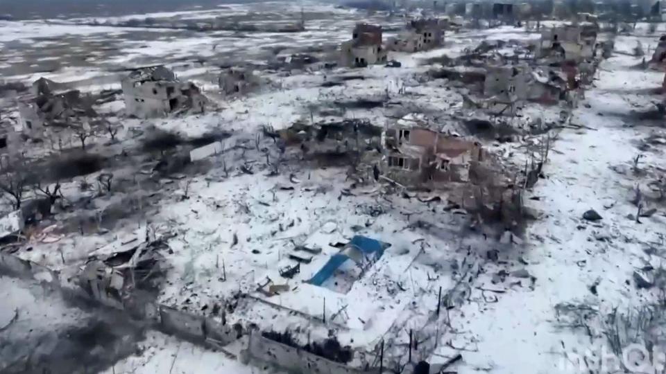 Seen from the air, Marina's damaged house and empty blue swimming pool - there is snow on the ground and other damaged building nearby.