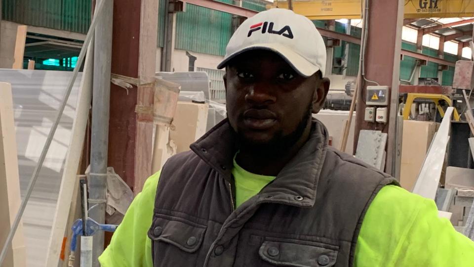 Migrant worker Makan, from Mali, looks into the camera in his work uniform at the Spanish firm he works for