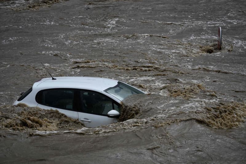 A flooded car stands in an industrial estate after heavy rainfall in the region. Jean-Philippe Ksiazek/AFP/dpa