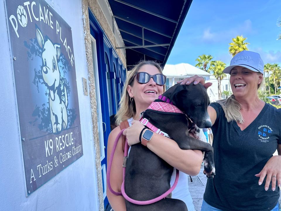 Author Terri Peters holding a puppy and smiling while a woman pets the dog 