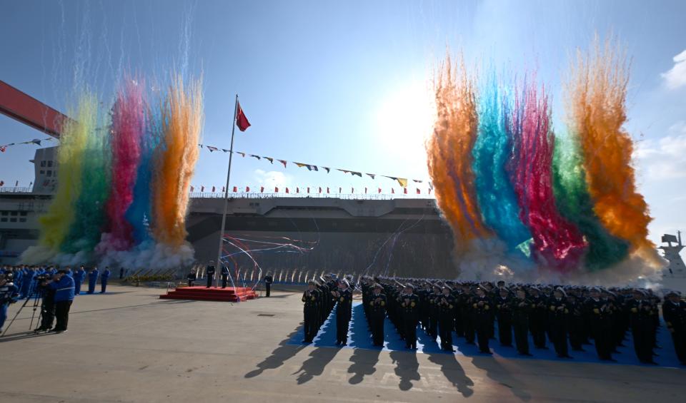 Plumes of colorful smoke surround the Sichuan during the amphibious assault ship's launching ceremony in China.