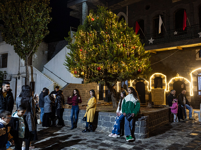 Syrians christians pose for a picture in front of a christmas tree at the Saint Mary Church of the Holy Belt in Homs on December 20, 2024. Islamist-led rebels took Damascus in a lightning offensive on December 8, ousting president Bashar al-Assad and ending five decades of Baath rule in Syria. (Photo by Sameer Al-DOUMY / AFP) (Photo by SAMEER AL-DOUMY/AFP via Getty Images)