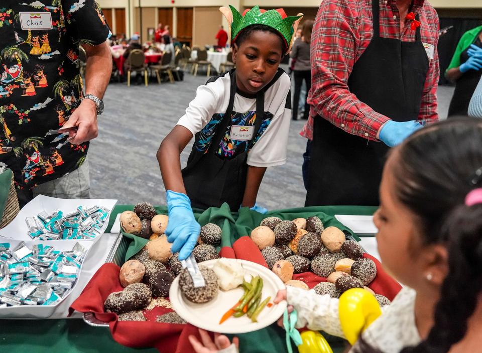 9-year-old Kristian Gainey of Desert Hot Springs serves dinner rolls to guests while volunteering at the event with his mom and siblings.