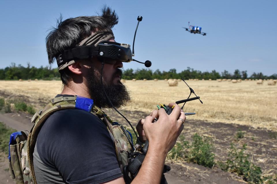 A drone operator of the 15th Brigade flies a drone used as a loitering munition in a wheat field.