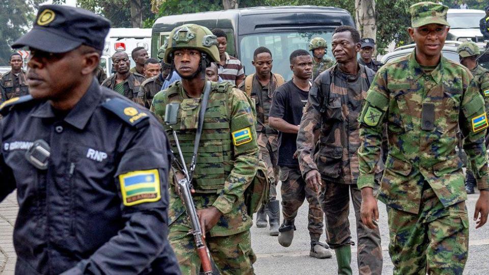 A Rwandan policeman and Rwandan army soldiers escort a group of Congolese soldiers into Gisenyi after they surrendered