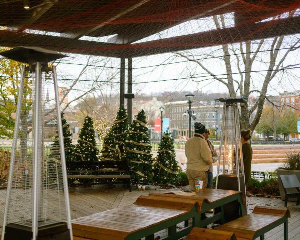 A group of people gather around the outdoor heaters at the Porch at Washington Park.