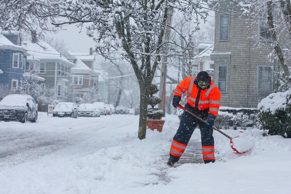 Ethan Oliveira shovels the snow from the sidewalk in New Bedford as a snow storm blankets the area.