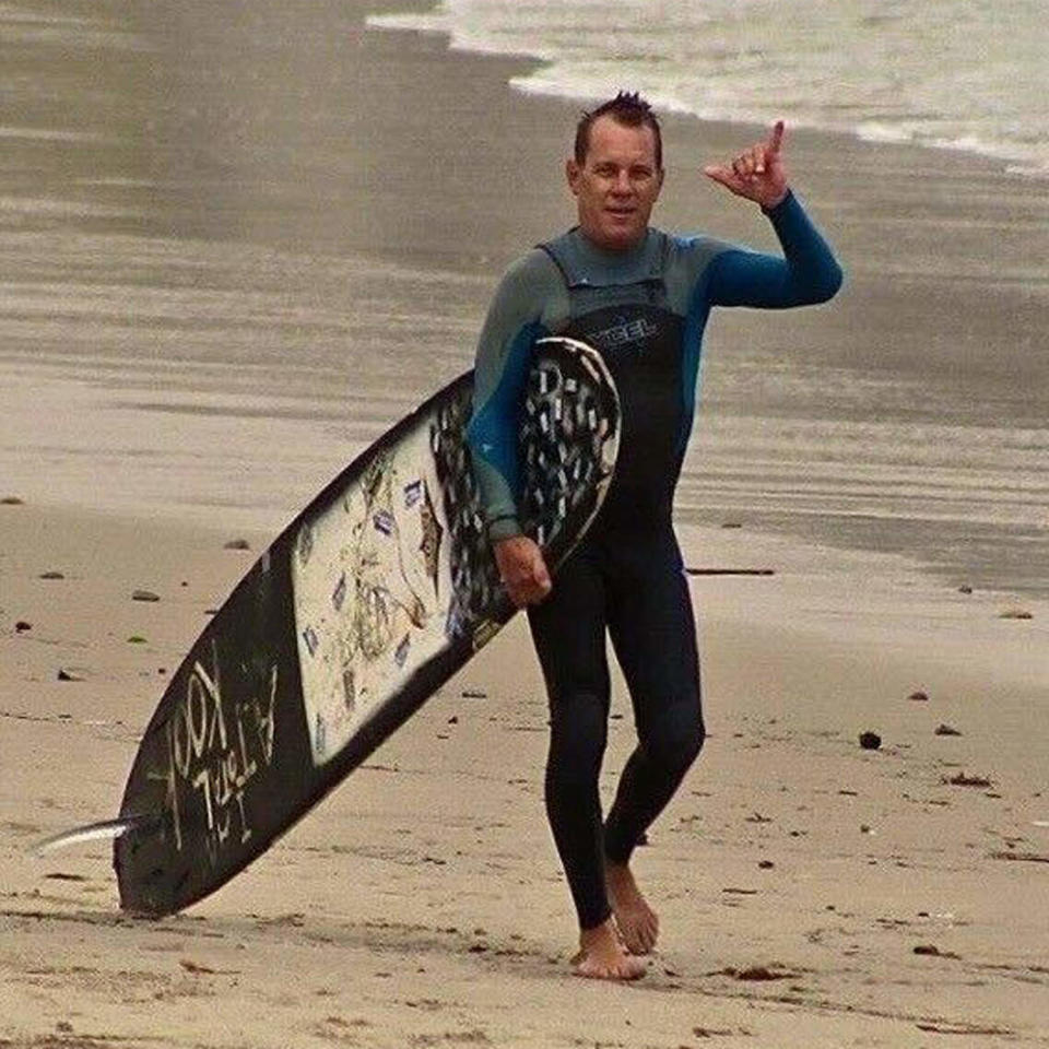 Randall Miod walks on the beach with a surfboard (Courtesy Carol Smith)