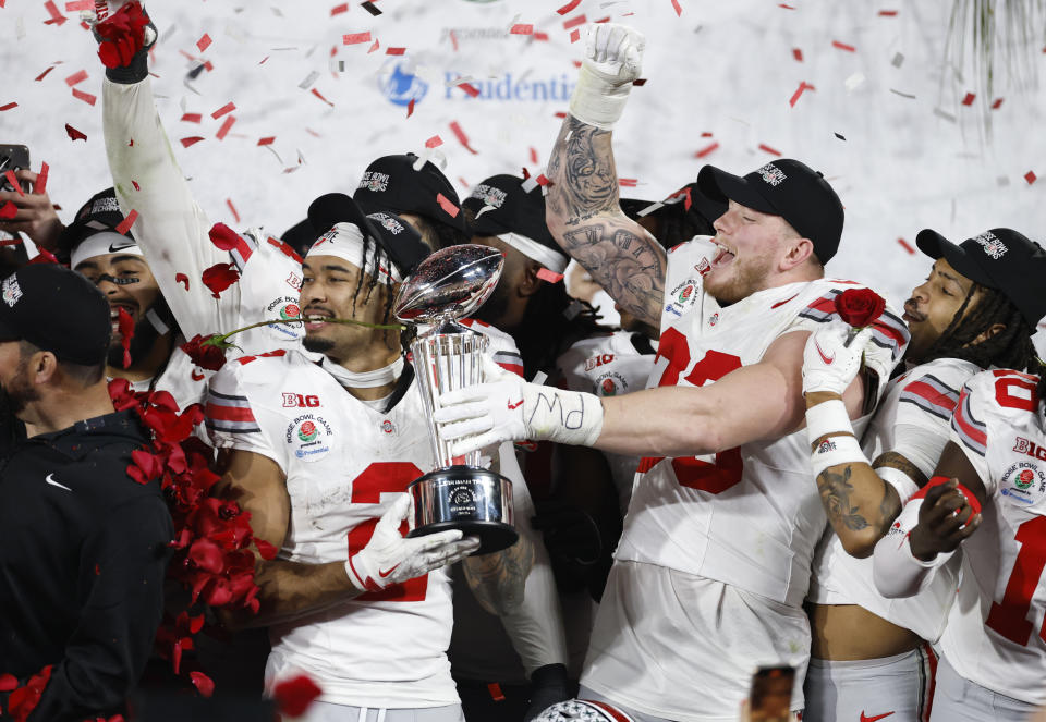 PASADENA, CALIFORNIA - JANUARY 01: Emeka Egbuka #2 and Jack Sawyer #33 of the Ohio State Buckeyes hold the Leishman Trophy after defeating the Oregon Ducks 41-21 during the Rose Bowl Game Presented by Prudential at Rose Bowl Stadium on January 01, 2025 in Pasadena, California. (Photo by Ronald Martinez/Getty Images)