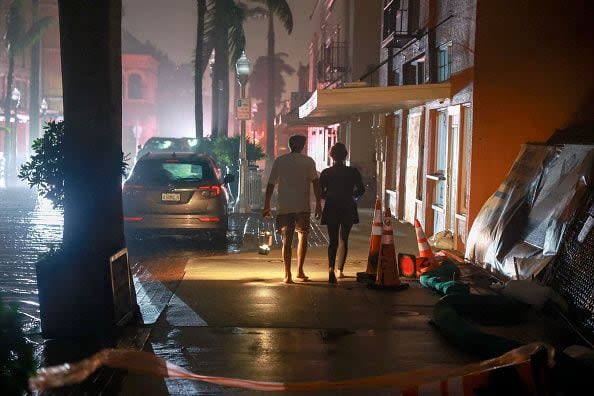 FORT MYERS BEACH, FLORIDA - OCTOBER 09: People walk along a street through the wind and rain after power was knocked as Hurricane Milton made landfall in the Sarasota area on October 09, 2024, in Fort Myers, Florida. Milton, coming on the heels of the destructive Helene, hit as a category 3 storm with winds of over 100 mph, though veering south of the projected direct hit on Tampa. Instead, the storm, which earlier had reportedly spawned tornadoes, landed about 70 miles south of Tampa near Siesta Key, a strip of white-sand beaches that's home to 5,500 people, according to published reports.. (Photo by Joe Raedle/Getty Images)