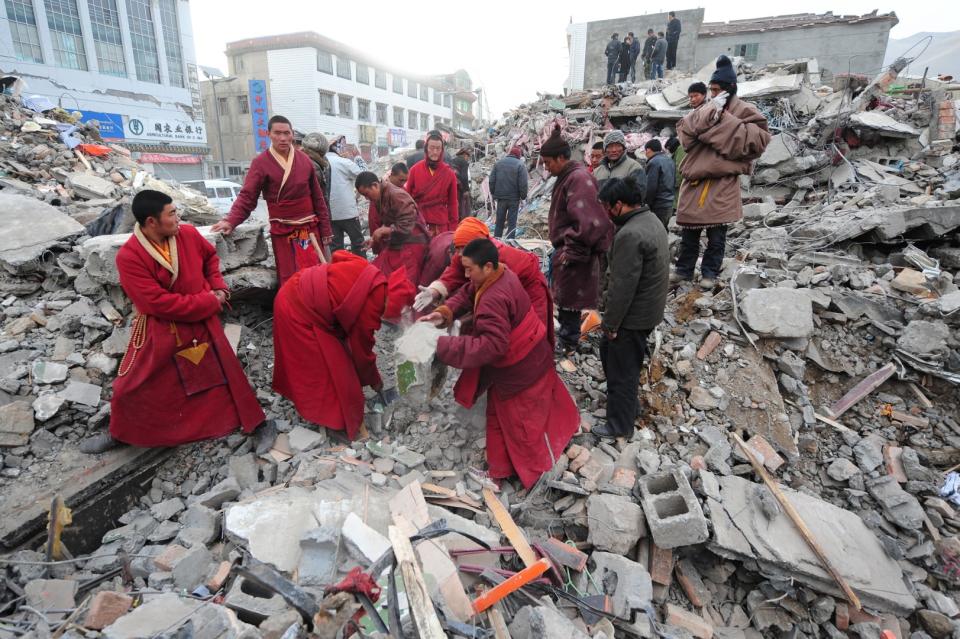 <span>Tibetan Buddhist monks clear debris while searching for survivors amid a collapsed apartment block in Jiegu, Yushu County on April 16, 2010</span><div><span>FREDERIC J. BROWN</span><span>AFP</span></div>