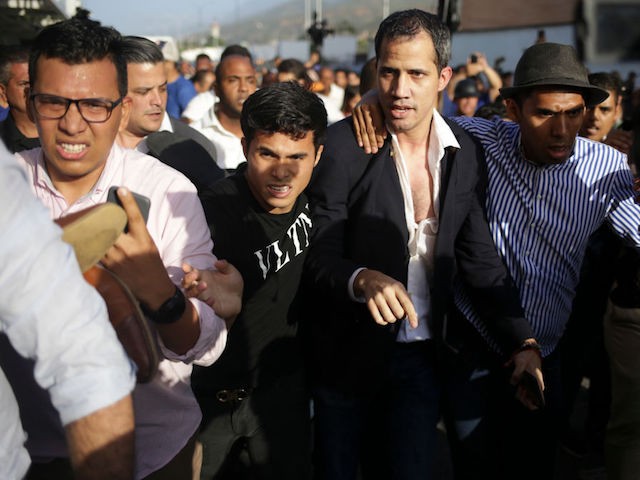 TOPSHOT - Venezuelan opposition leader and self-proclaimed acting president Juan Guaido is escorted to his car after arriving at Simon Bolivar International Airport in Maiquetia, Vargas state, Venezuela on February 11, 2020. - Guaido returned to Venezuela after a 23-day international tour to revitalize pressure on President Nicolas Maduro, his press team announced. (Photo by Cristian Hernandez / AFP) (Photo by CRISTIAN HERNANDEZ/AFP via Getty Images)