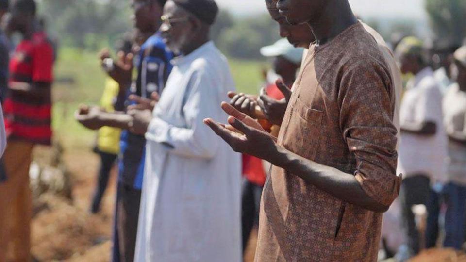 Male Muslim mourners hold up their hands in prayer as they attend a funeral at Tudun Wada cemetery 