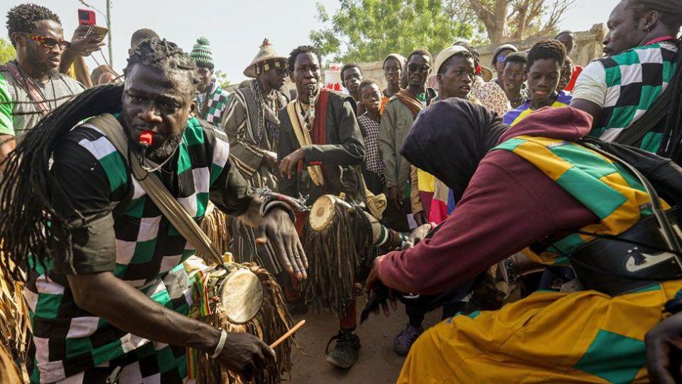 Baye Fall followers, some in colourful patchwork clothes, drumming and whistling on a street in Diourbel, Senegal