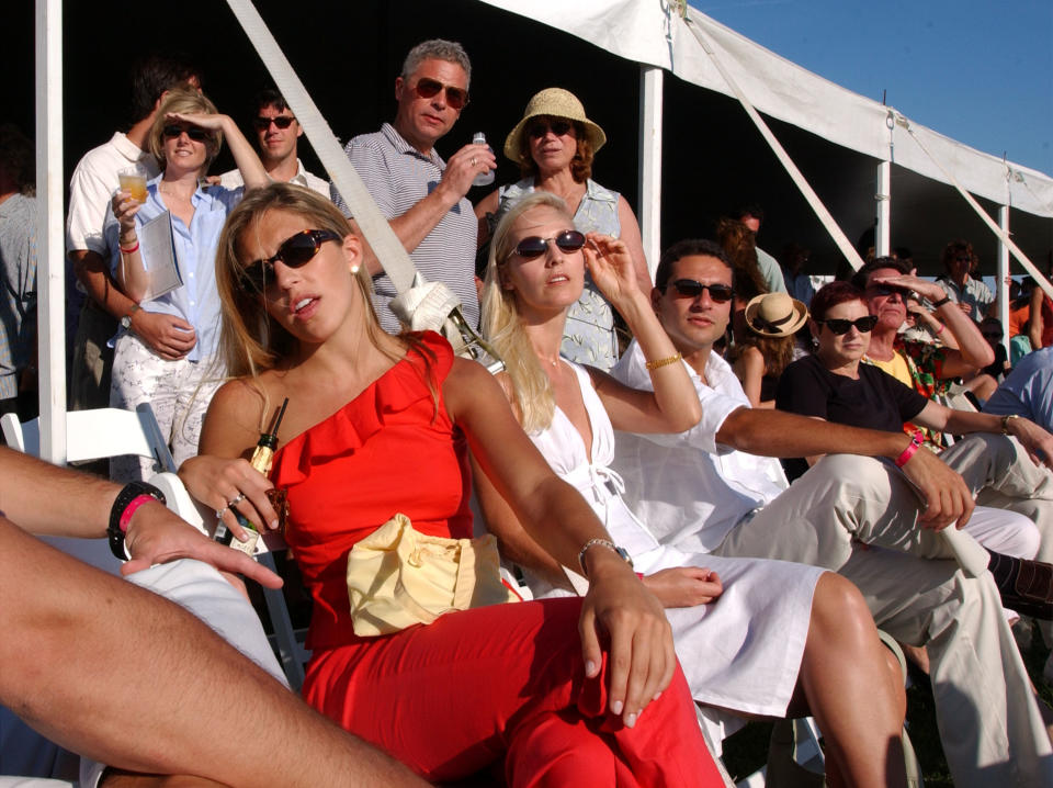 A group of wealthy people sit outdoors at an event