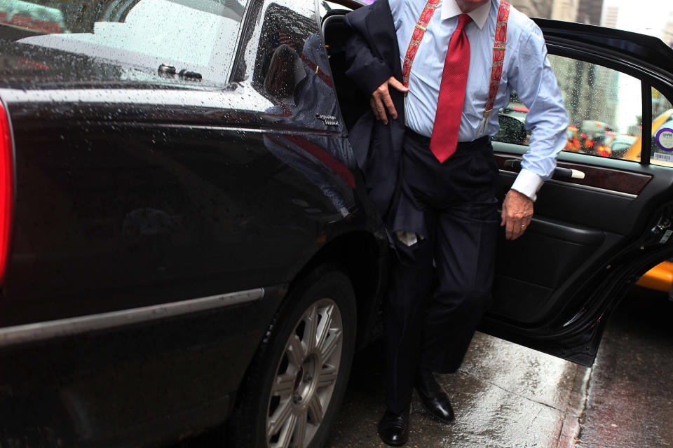 A person in formal attire exits a car on a rainy day