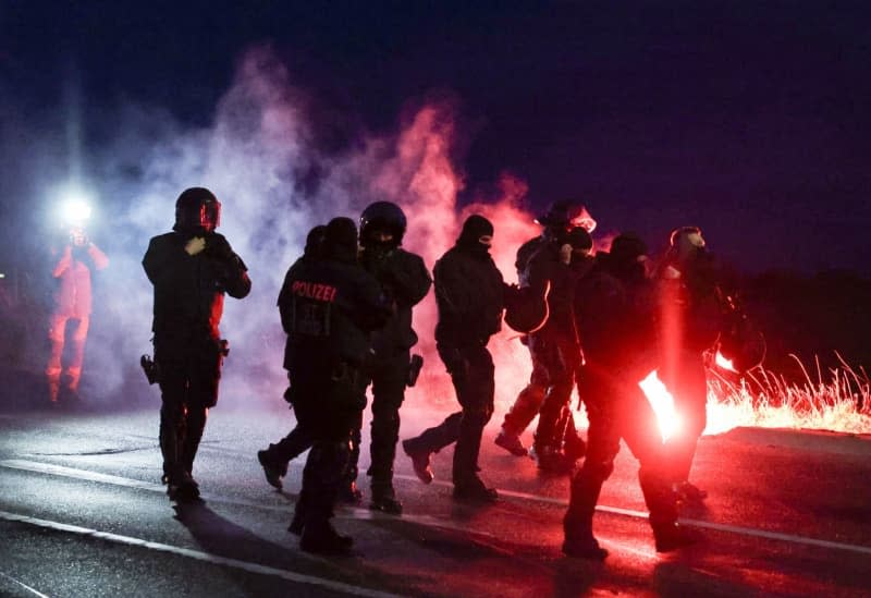 Police officers walk alongside burning pyrotechnics during a demonstration against the AfD's (Alternative for Germany) national party conference. The party conference is to adopt the party's parliamentary election program and nominate co-chair Weidel as candidate for chancellor. Jan Woitas/dpa