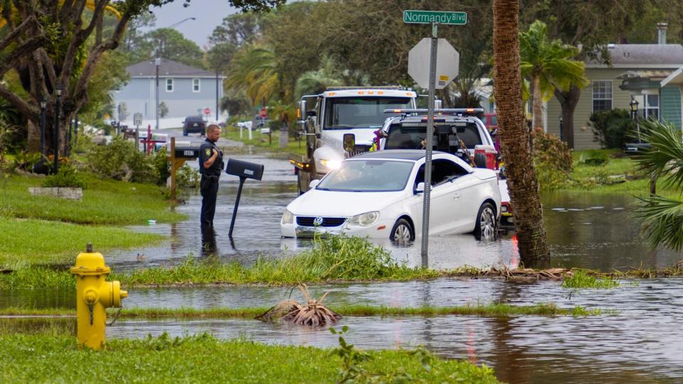 Police watch as a car is towed in Port Orange, FL following Hurricane Milton in Oct. 2024.