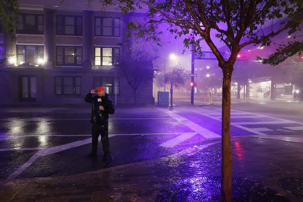 TAMPA, FLORIDA - OCTOBER 09: A television reporter stands on a downtown street as Hurricane Milton makes landfall on October 09, 2024, in Tampa, Florida. Milton, coming on the heels of the destructive Helene, hit as a category 3 storm with winds of over 100 mph, though avoiding the projected direct hit on Tampa. Instead, the storm, which earlier had reportedly spawned tornadoes, landed about 70 miles south of Tampa near Siesta Key, a strip of white-sand beaches that's home to 5,500 people, according to published reports.  (Photo by Spencer Platt/Getty Images)