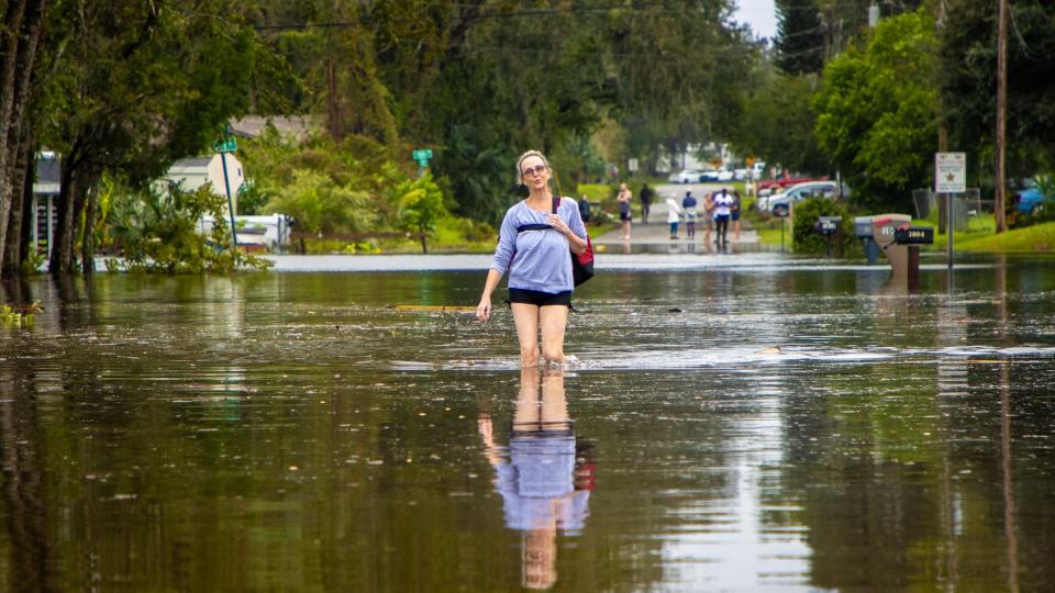 A woman walks through flood waters to get food after Hurricane Milton blew through South Daytona, FL in Oct. 2024.