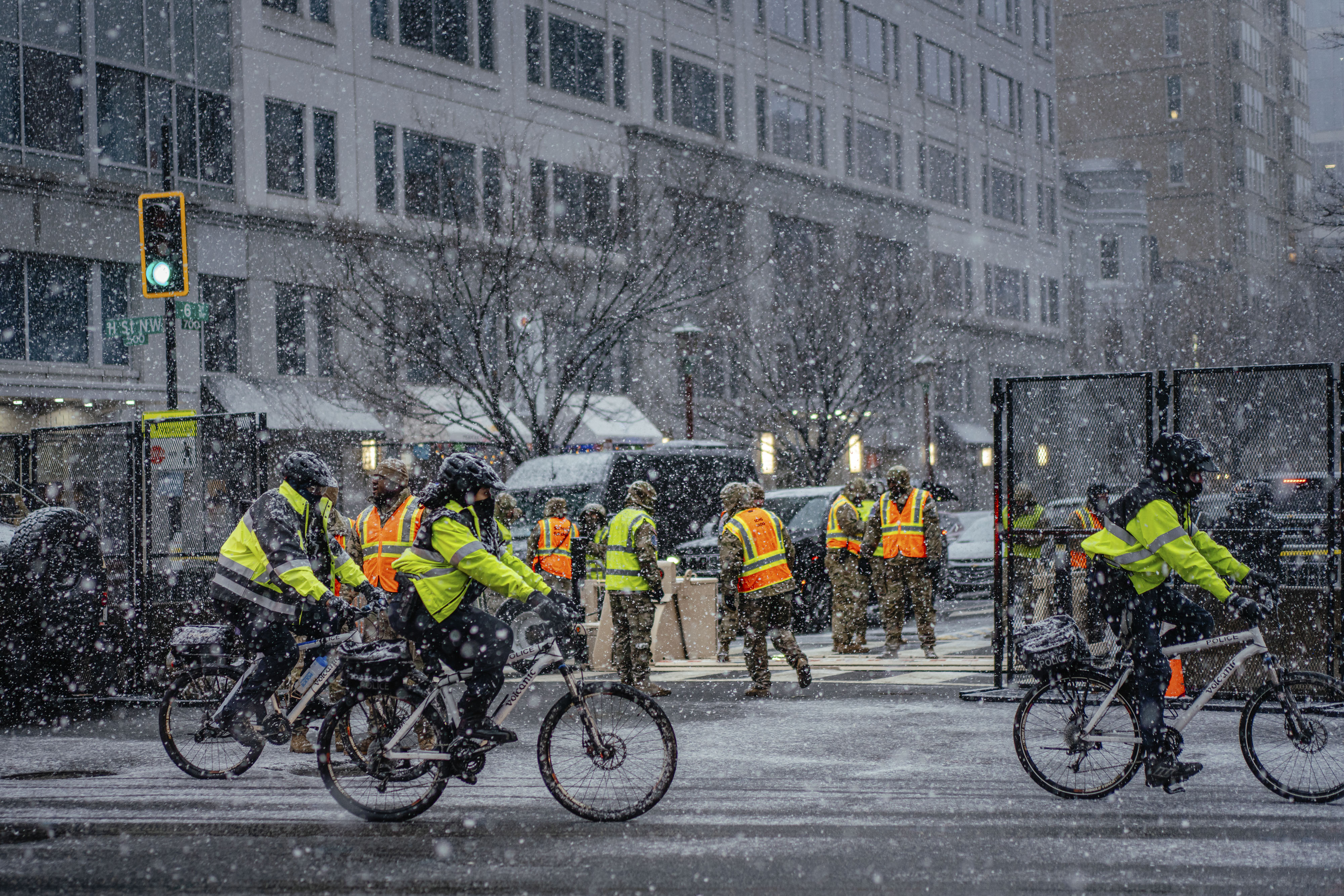 Heavy snow falls as police officers bike around Capital One Arena.