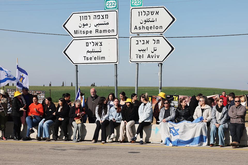 People carrying national flags line a street awaiting for the funeral procession of the Bibas' in kibbutz Nir Oz in southern Israel on February 26, 2025.  (Jack Guez / AFP via Getty Images)