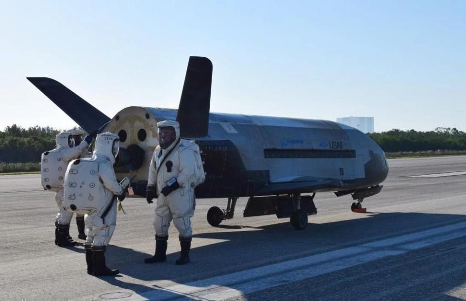 Personnel wearing protective gear surrounded the X-37B after it landed on the runway at NASA's Kennedy Space Center.