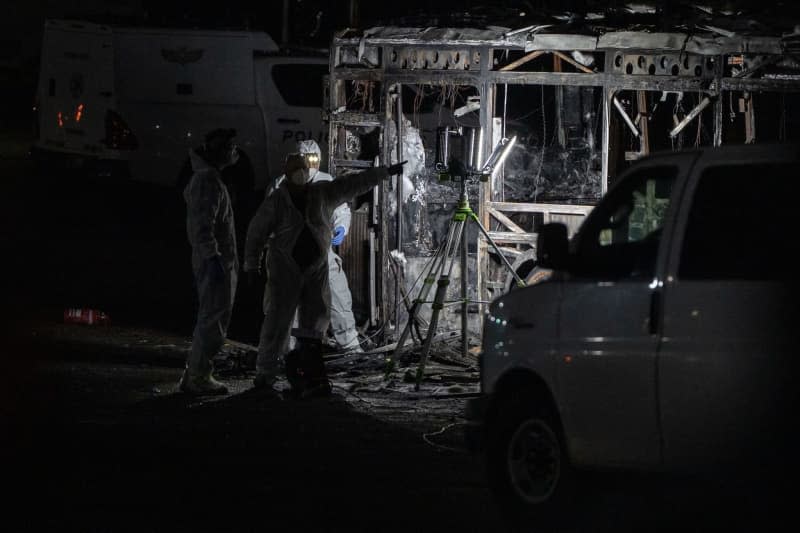 Israeli forensics officers inspect one of the three empty buses that exploded in Tel Aviv's southern suburb of Bat Yam. Ilia Yefimovich/dpa