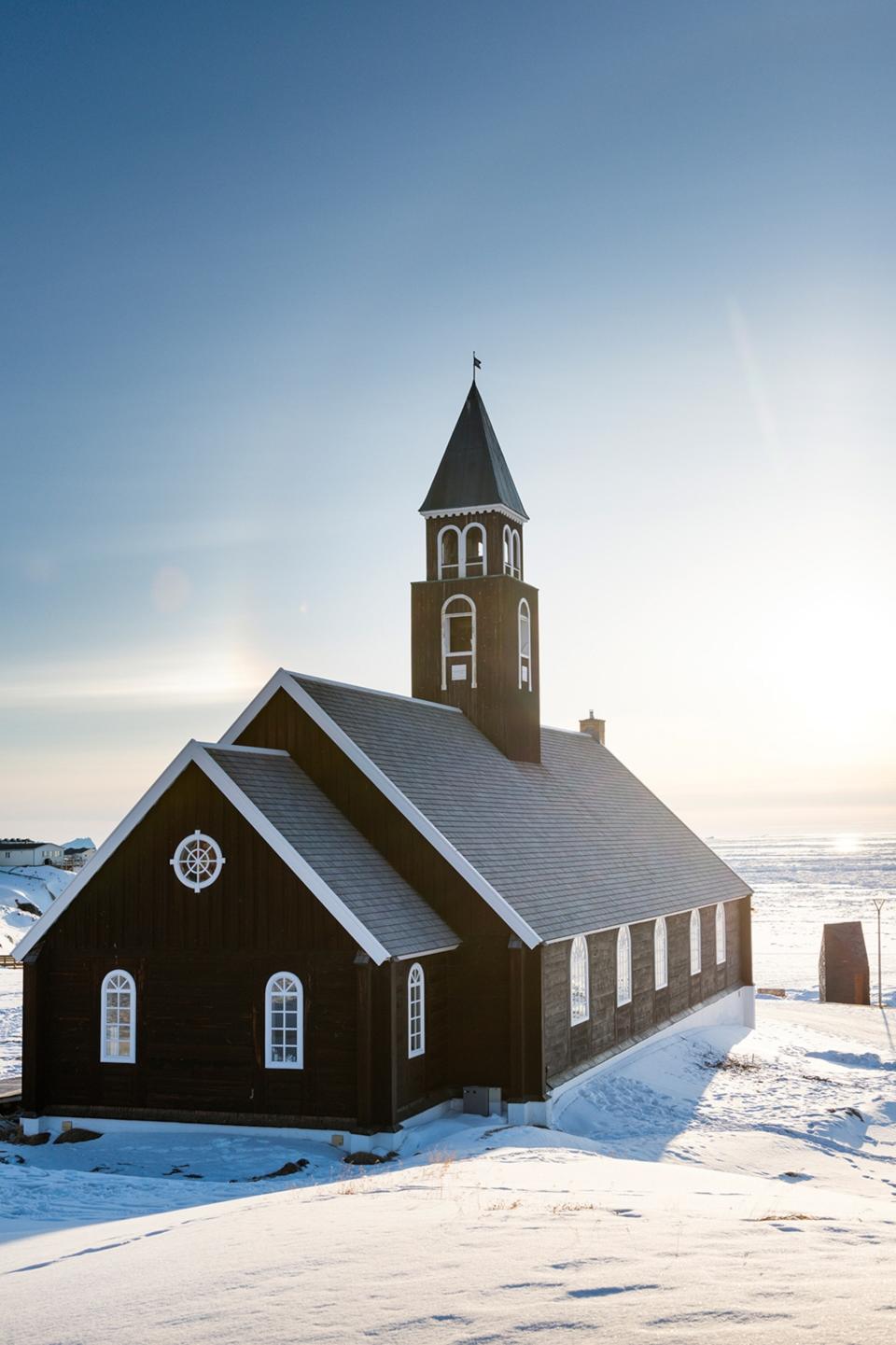 A modest, wooden church in a vast snowy landscape.