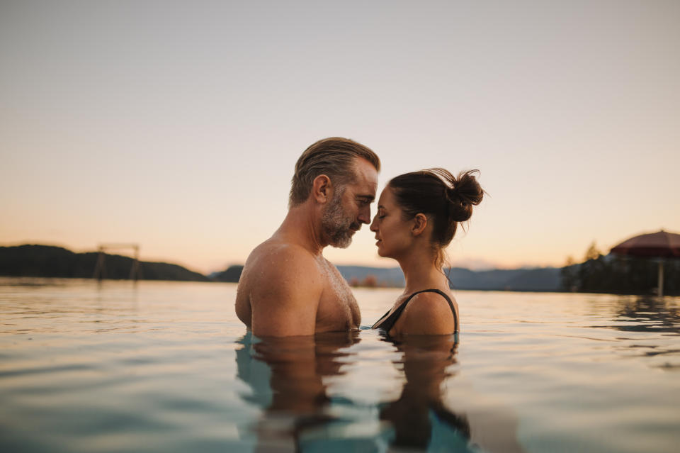 A couple in the infinity pool at Chalet Mirabell, gazing into each other’s eyes with the Dolomites in the background.