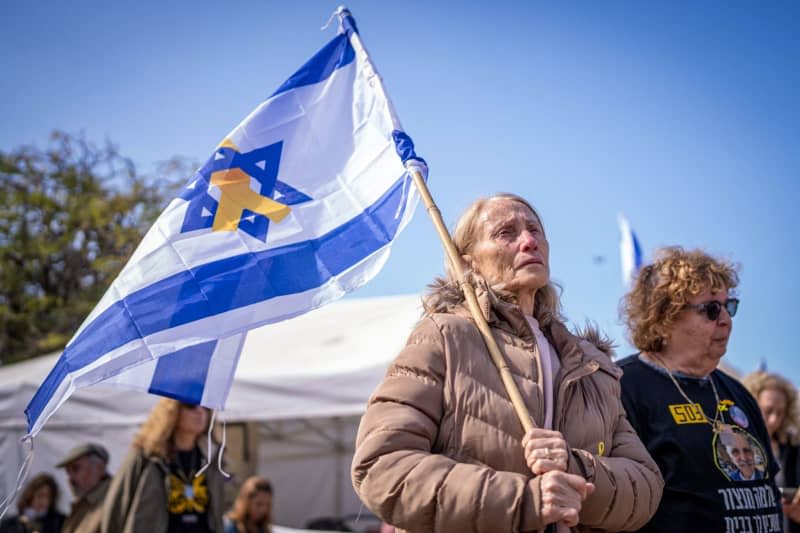 A person cries while holding an Israeli flag at Hostage Square in Tel Aviv ahead of the expected release of the remains of four Israeli hostages by Hamas. According to Hamas, the dead include a mother and two toddlers of German nationality. The Israeli army has already recovered several hostage bodies in the Gaza Strip and brought them back to Israel. Ilia Yefimovich/dpa