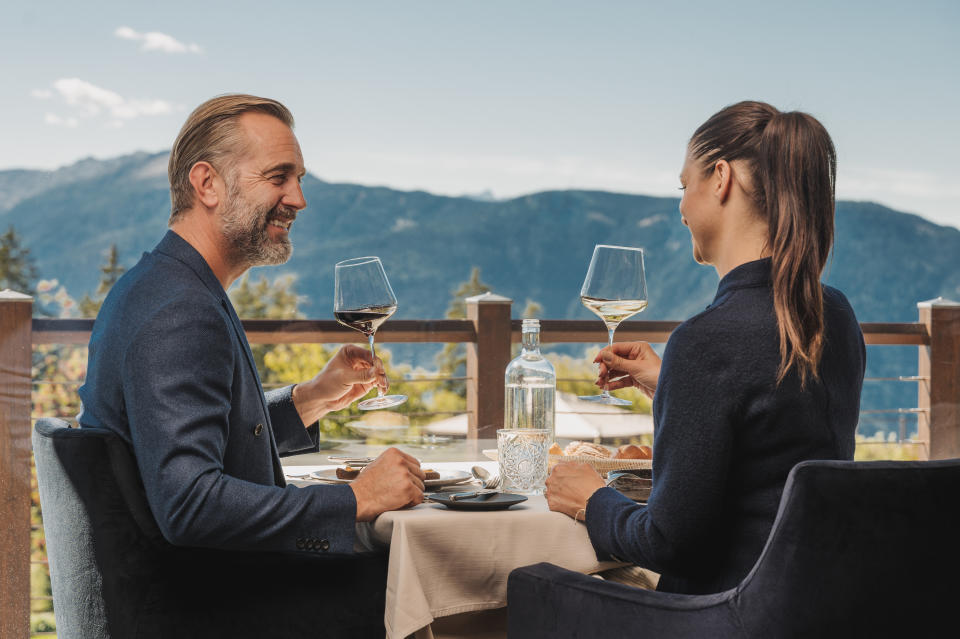 A couple enjoying fine dining at Chalet Mirabell with stunning mountain views in the background.