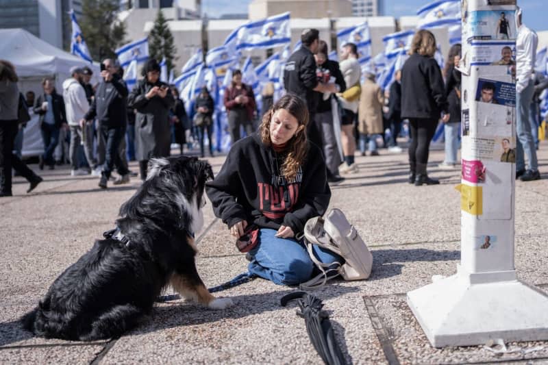 A woman plays with her dog at Hostage Square in Tel Aviv ahead of the expected release of the remains of four Israeli hostages by Hamas. According to Hamas, the dead include a mother and two toddlers of German nationality. The Israeli army has already recovered several hostage bodies in the Gaza Strip and brought them back to Israel. Ilia Yefimovich/dpa