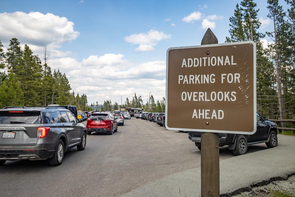 Parking Sign at Grand Canyon of Yellowstone River in Yellowstone National Park, Wyoming, with car number plates visible.