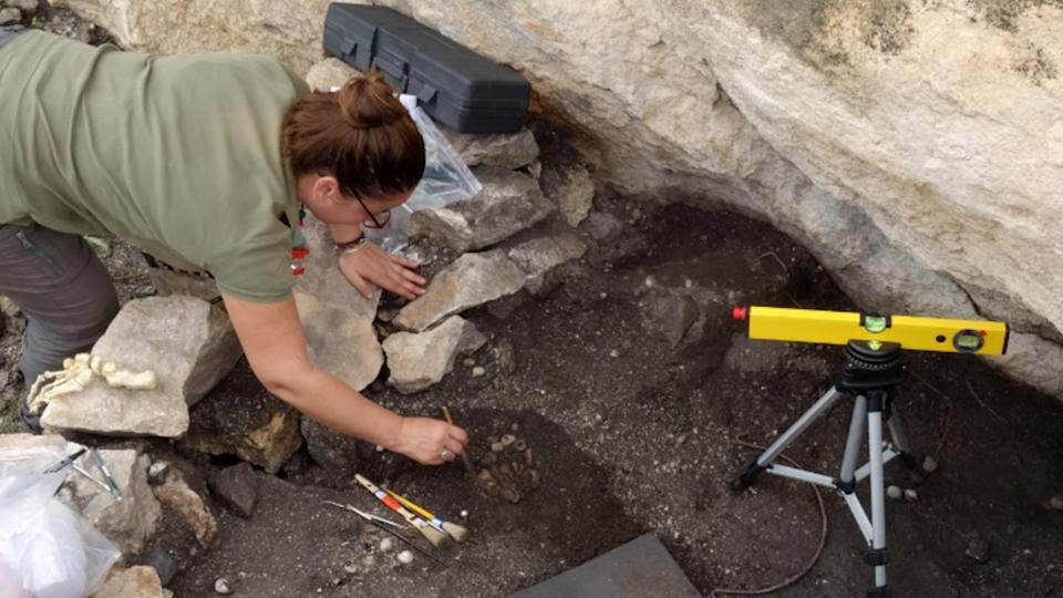 a woman excavates human remains