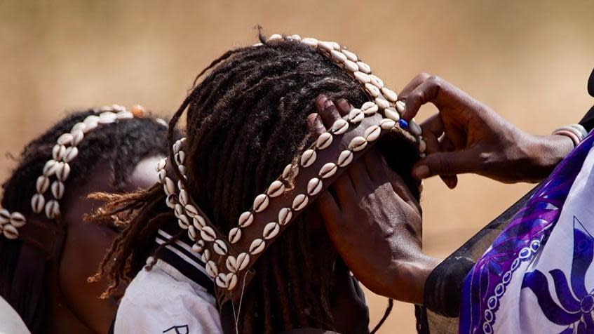 A mother puts a cowrie-shell headpiece on her son for the festivities.