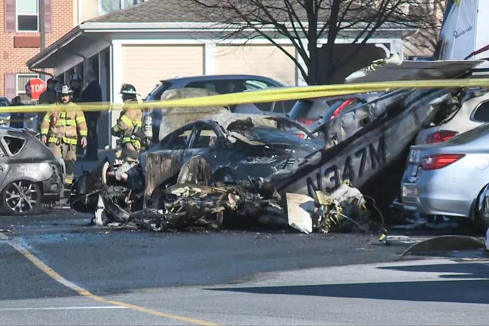 A damaged car in a parking lot next to a piece of plane debris (NBC News)