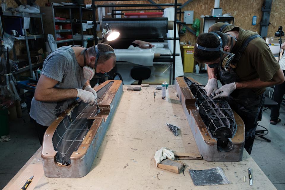 Two men work on drone components over a wooden table