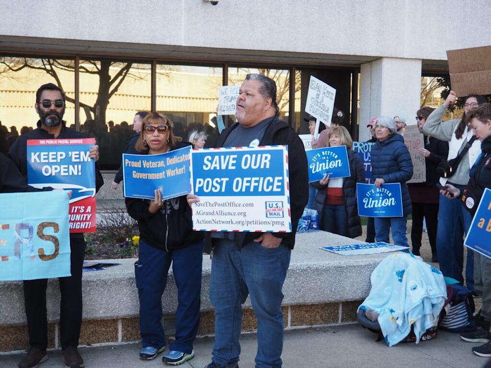 Protesters hold signs reading “Save Our Post Office” and “It’s Better in a Union.”