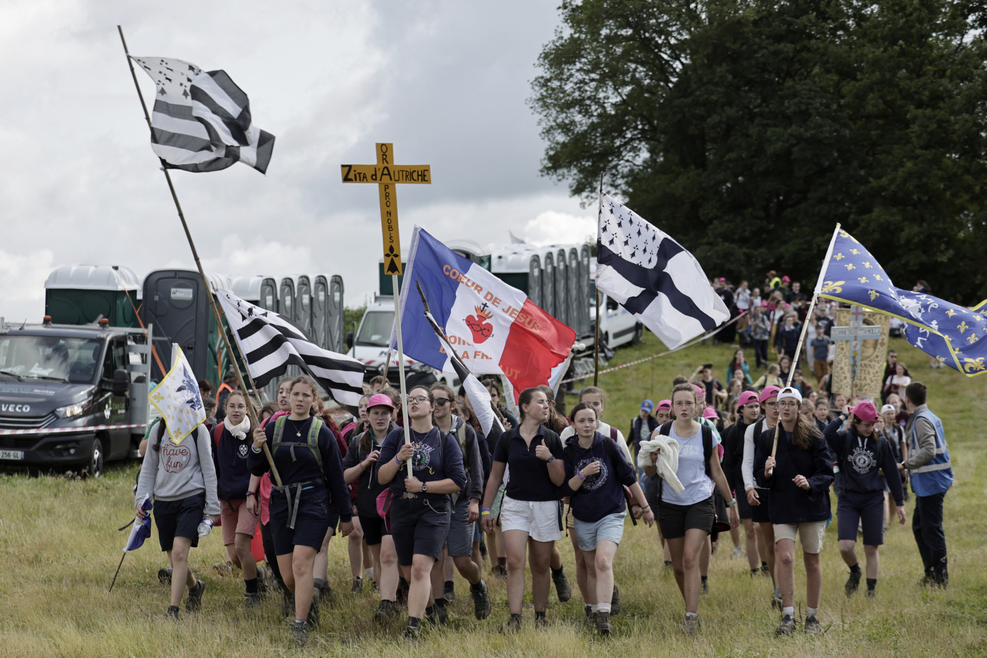 Pelgrins hold crosses, banners and flags as they arrive for the Mass, during the traditional Pentecostal pilgrimage from Paris to Chartres, in Sonchamp, near Paris, on June 8, 2025. From the church of Saint-Sulpice in Paris, thousands of people began their march towards Chartres on June 7, 2025 for the great traditionalist pilgrimage, which is attracting a record 19,000 Catholics this year, despite certain tensions with the episcopate. (Photo by STEPHANE DE SAKUTIN / AFP) (Photo by STEPHANE DE SAKUTIN/AFP via Getty Images)