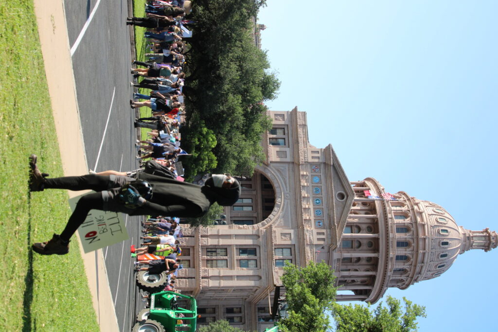 Masked protester carries helmet across Texas Capital grounds at Democrats No Kings Rally (Randy Clark/Breitbart Texas)