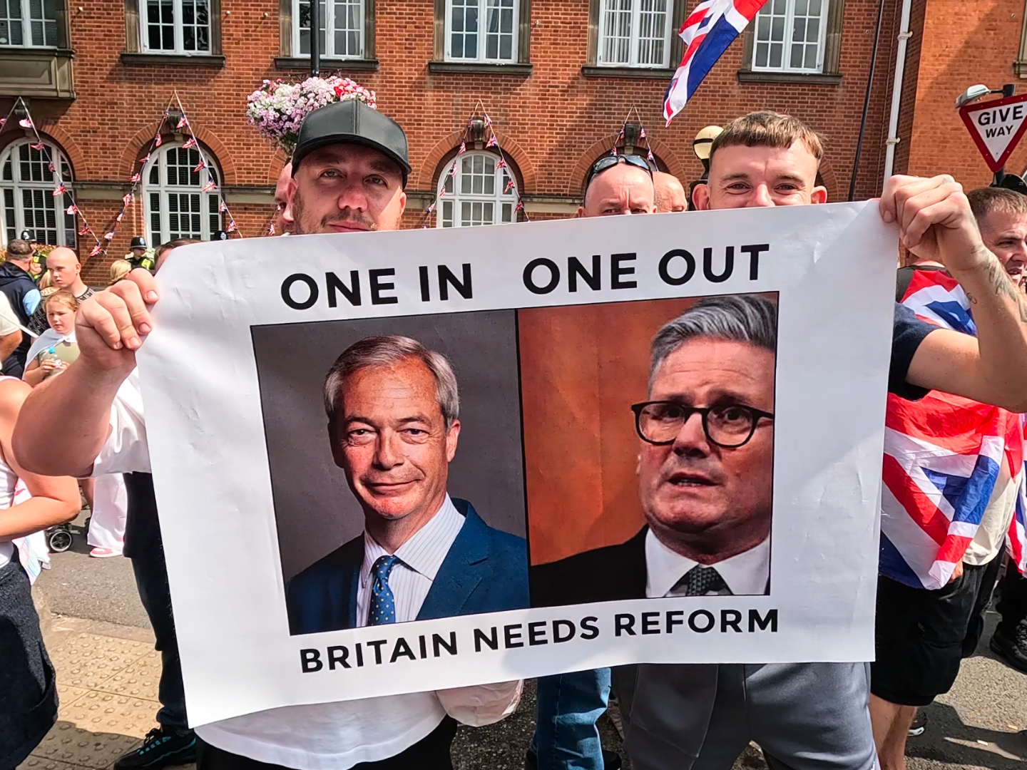Demonstrators in Nuneaton hold sign mocking Prime Minister Keir Starmer's migration policy and advocating for Reform UK leader Nigel Farage. August 9th, 2025. Oliver Lane Breitbart News