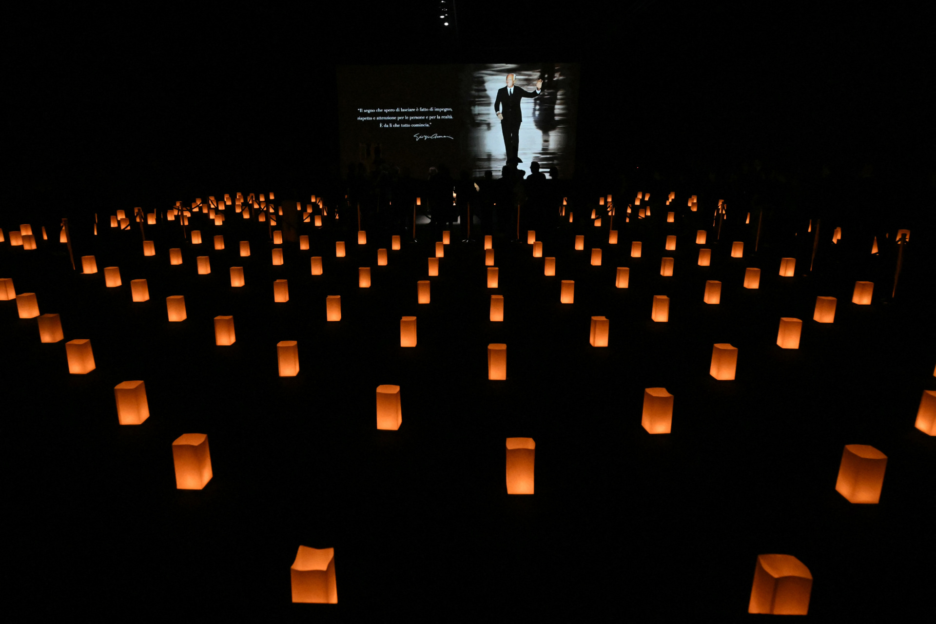 People queue to see the coffin of late Italian fashion designer Giorgio Armani lying-in state for two days at the Armani Theatre in Milan as a picture of him is seen on a screen, on September 6, 2025. Giorgio Armani died on September 4, 2025 at 91. (Photo by Stefano RELLANDINI / AFP) (Photo by STEFANO RELLANDINI/AFP via Getty Images)