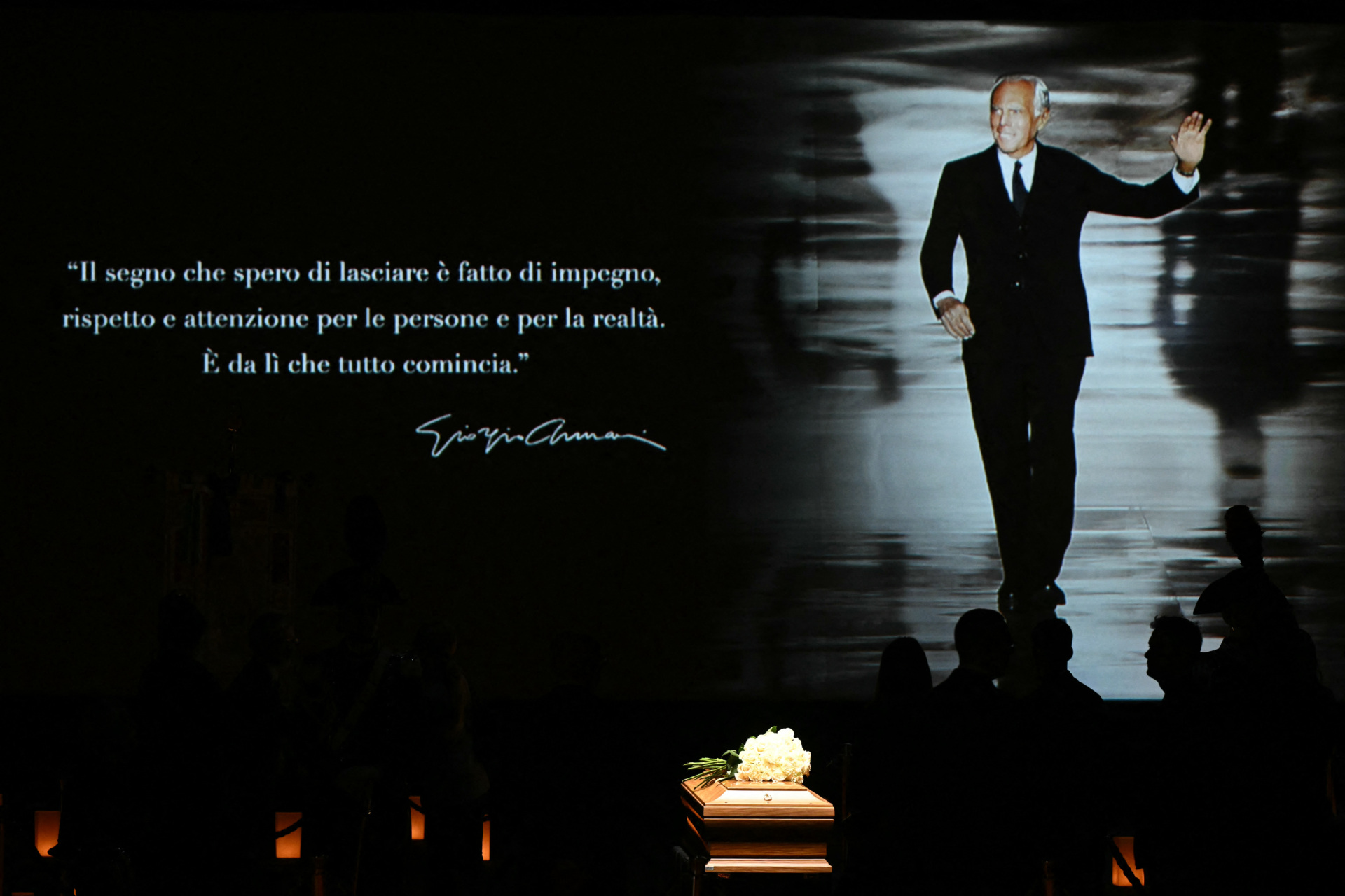 TOPSHOT - People queue to see the coffin of late Italian fashion designer Giorgio Armani lying-in state for two days at the Armani Theatre in Milan as a picture of him is seen on a screen, on September 6, 2025. The screen reads "The mark I hope to leave is one of commitment, respect, and genuine care for people and for reality. "That's where everything truly begins.". Giorgio Armani died on September 4, 2025 at 91. (Photo by Stefano RELLANDINI / AFP) (Photo by STEFANO RELLANDINI/AFP via Getty Images)