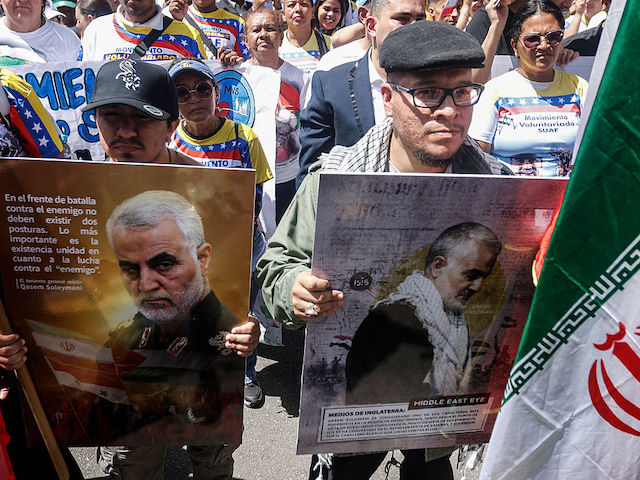Two men hold posters with the image of the late Iranian General Qasem Soleimani during a rally in solidarity with Iran and the Palestinian people and to demand a ceasefire by Israel, at the Iranian embassy in Caracas on June 17, 2025. Israel and Iran exchanged fire again on June 17, the fifth day of strikes in their most intense confrontation in history, fuelling fears of a drawn-out conflict that could engulf the Middle East. (Photo by Pedro MATTEY / AFP)