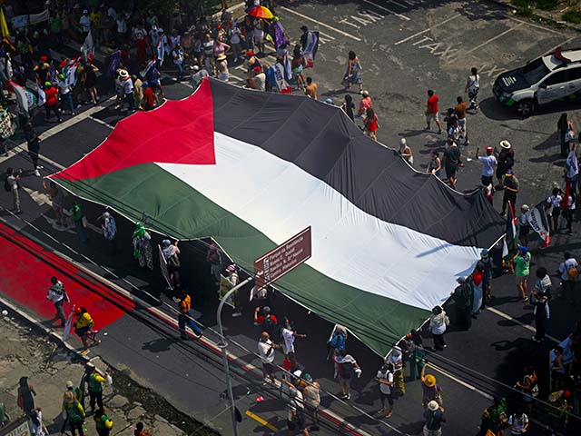 Activists carry a huge Palestinian flag during the so-called "Great People's March" in the sidelines of the COP30 UN Climate Change Conference in Belem, Para State, Brazil on November 15, 2025. Thousands of people attended the march to demand "real solutions" to human-caused global warming , and which comes at the halfway point of contentious COP30 negotiations following two Indigenous-led protests that disrupted proceedings earlier in the week. (Photo by Mauro PIMENTEL / AFP) (Photo by MAURO PIMENTEL/AFP via Getty Images)