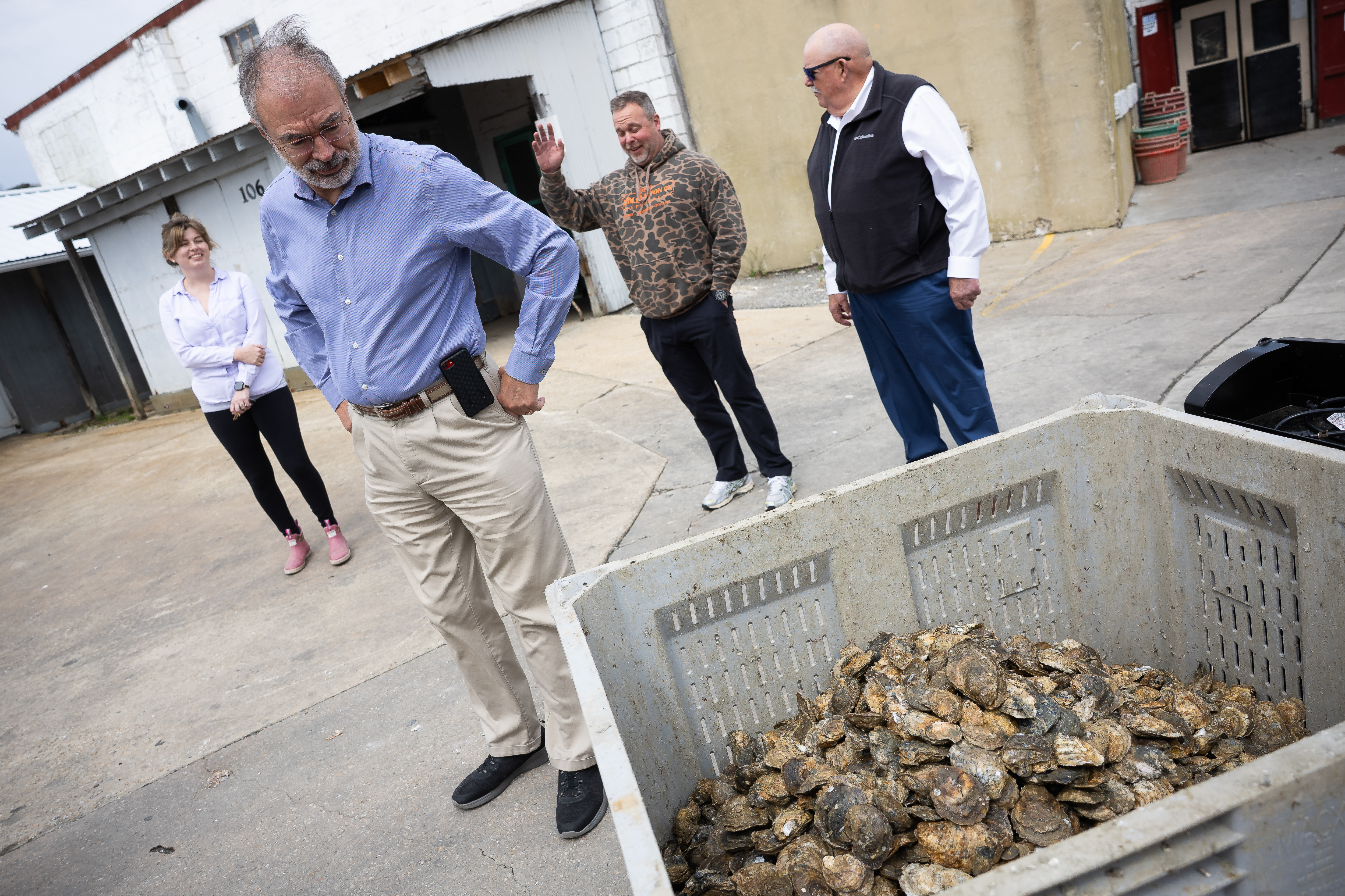 Harris examines a container of live oysters during a tour of the J.M. Clayton Company's crab processing plant.