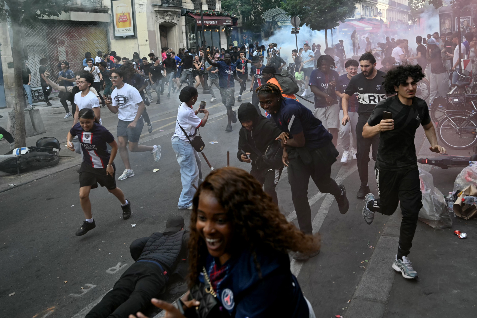 PSG supporters run from the teargas fired by French police during the UEFA Champions League final football match between Paris Saint-Germain (PSG) and Arsenal FC , in Paris on May 30, 2026. (Photo by LOU BENOIST / AFP via Getty Images)